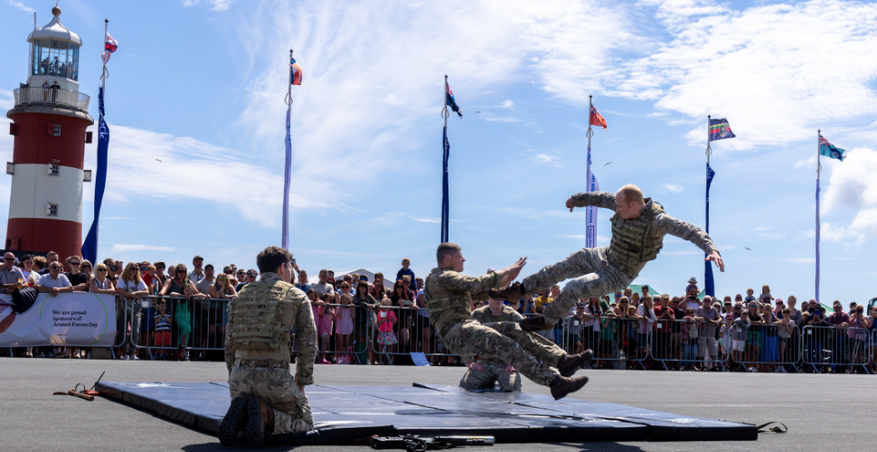 The Royal Marines Unarmed Combat Display on Plymouth Hoe with people watching on and the top of Smeaton's Tower in the background